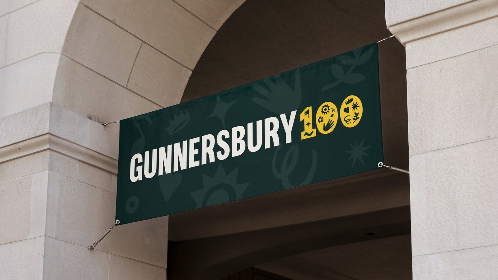 Gunnersbury 100 signage with teal and gold branding mounted on a stone archway entrance