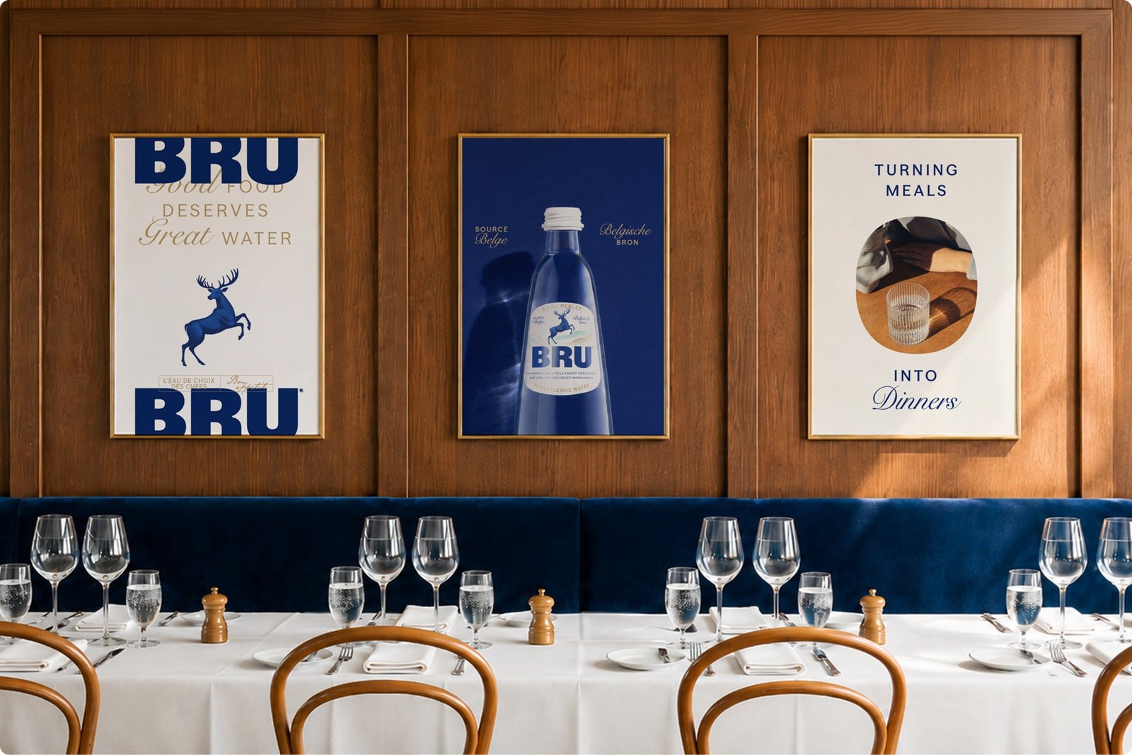 Three framed vintage-style BRU sparkling water posters and advertisements displayed on a wood-panelled wall above a formally set dining table with white tablecloths and glassware