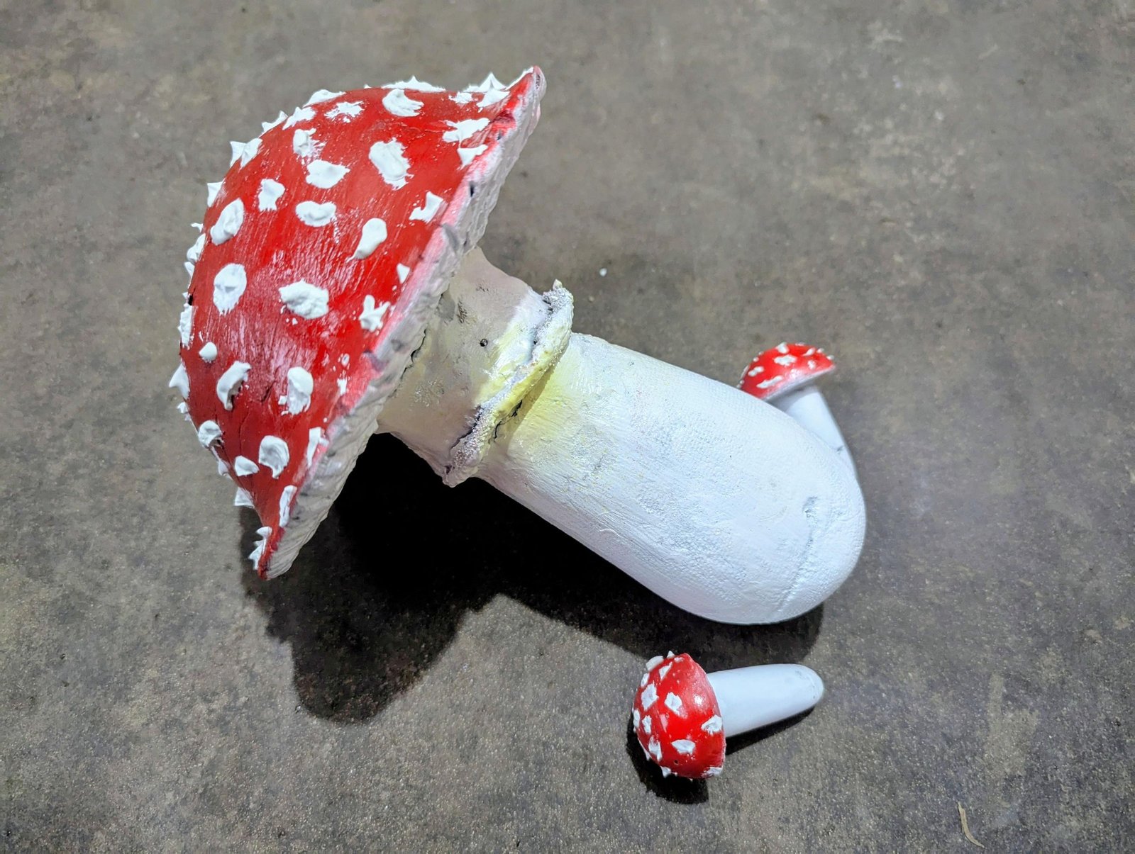 Finished red-and-white cement mushroom trio viewed from the spotted cap side