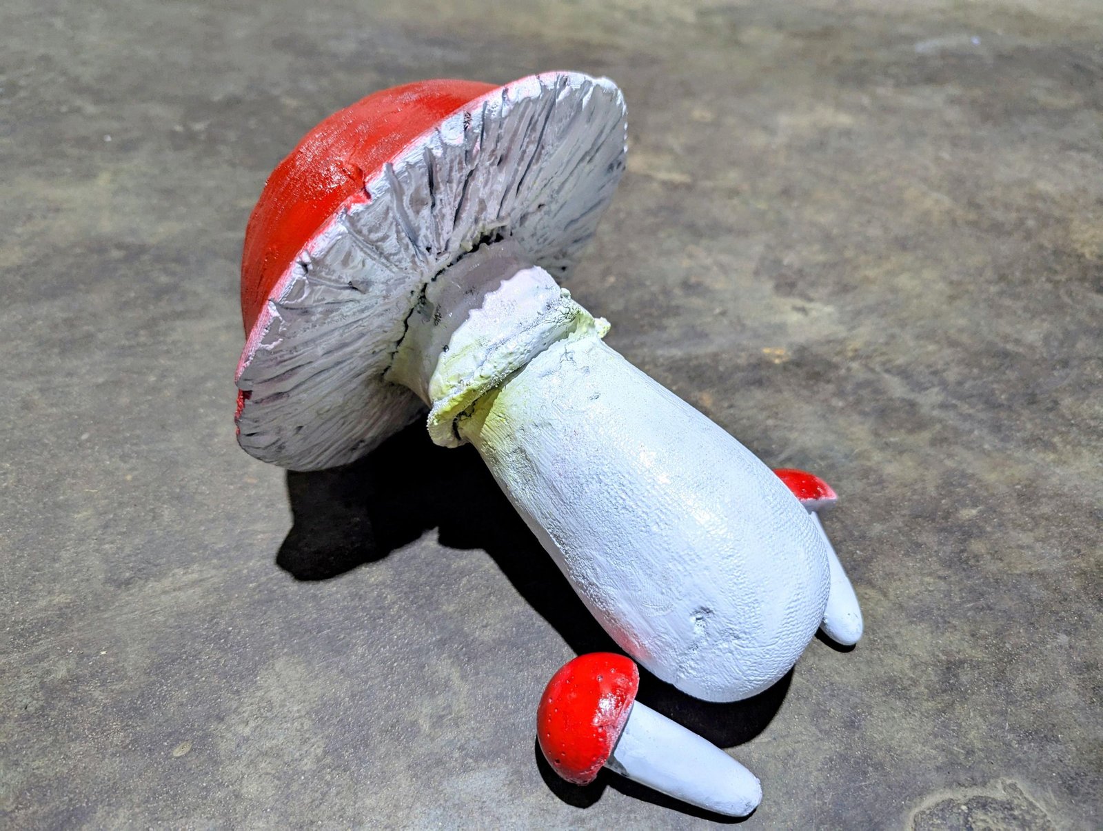 Finished cement mushrooms showing the carved white gills beneath the large red cap