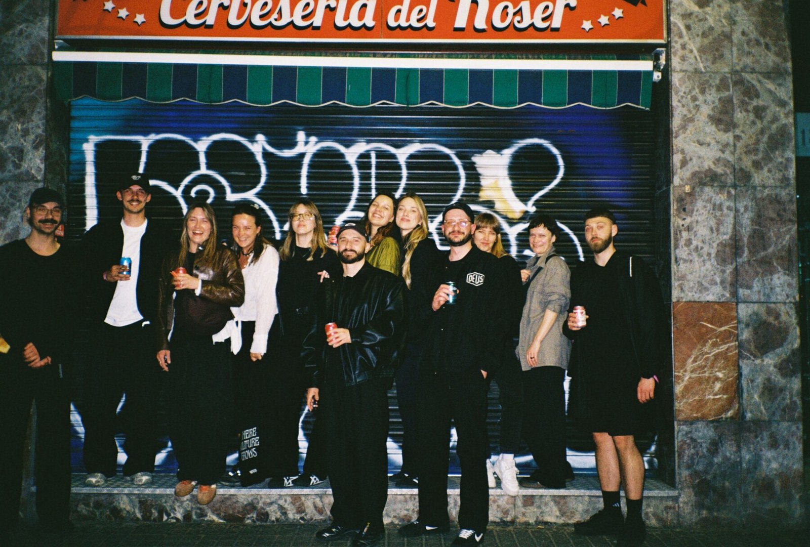 andstudio team and winery staff posing together outside Cervesería del Noser with graffiti-covered shutter behind them