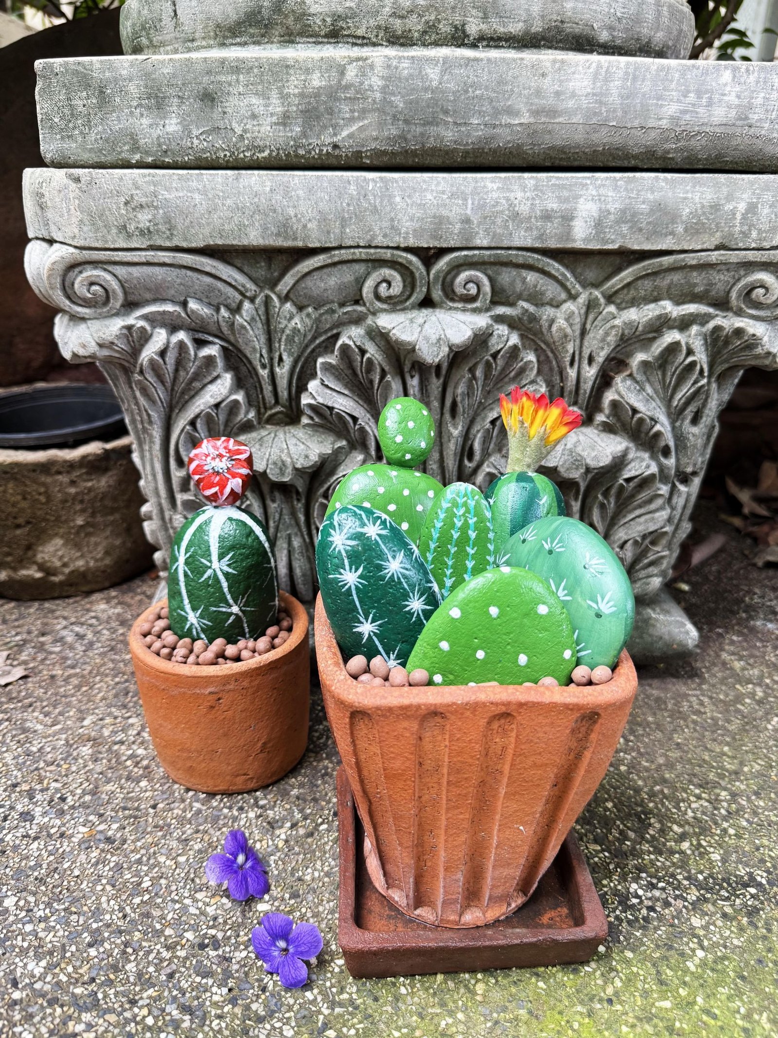 Two completed stone cactus planters displayed outdoors in front of carved garden stonework