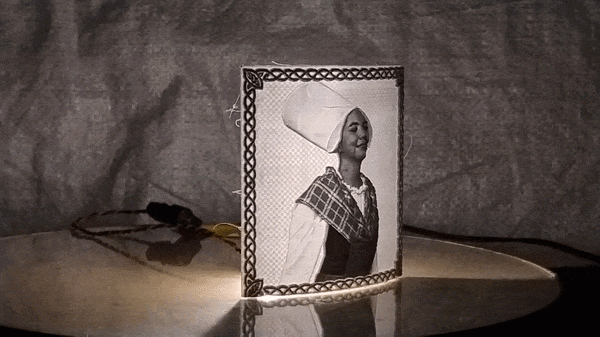 Finished framed lithophane portrait glowing on a round table in a dimly lit room