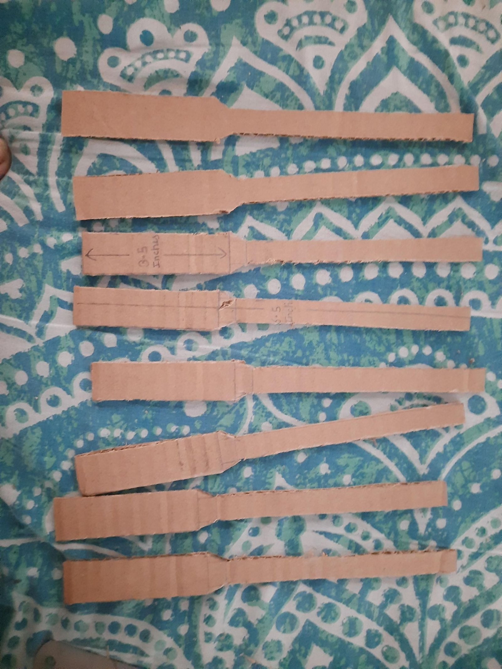 A matching set of cut cardboard fan ribs arranged on patterned cloth