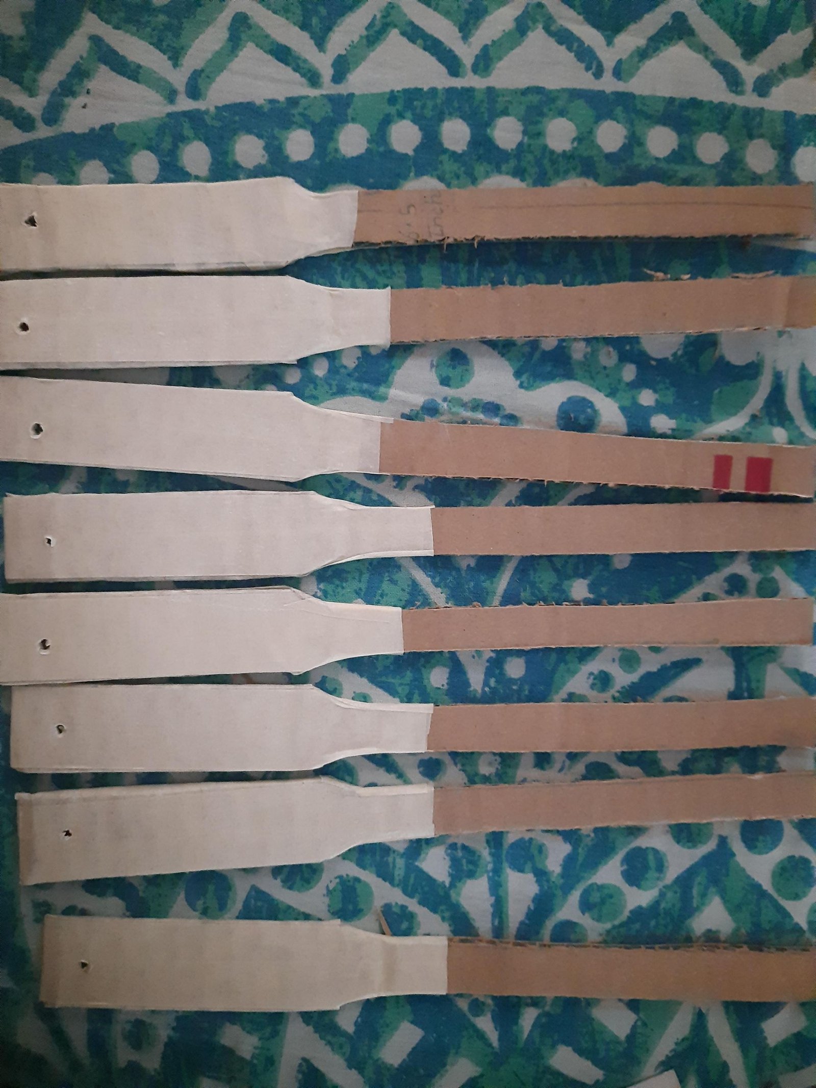 Cardboard fan ribs with their wider handle sections reinforced in white paper