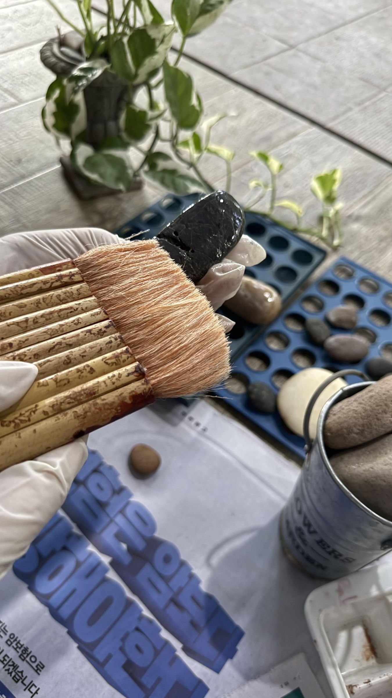 Brushes, primer, and prepared stones arranged on a protected work surface