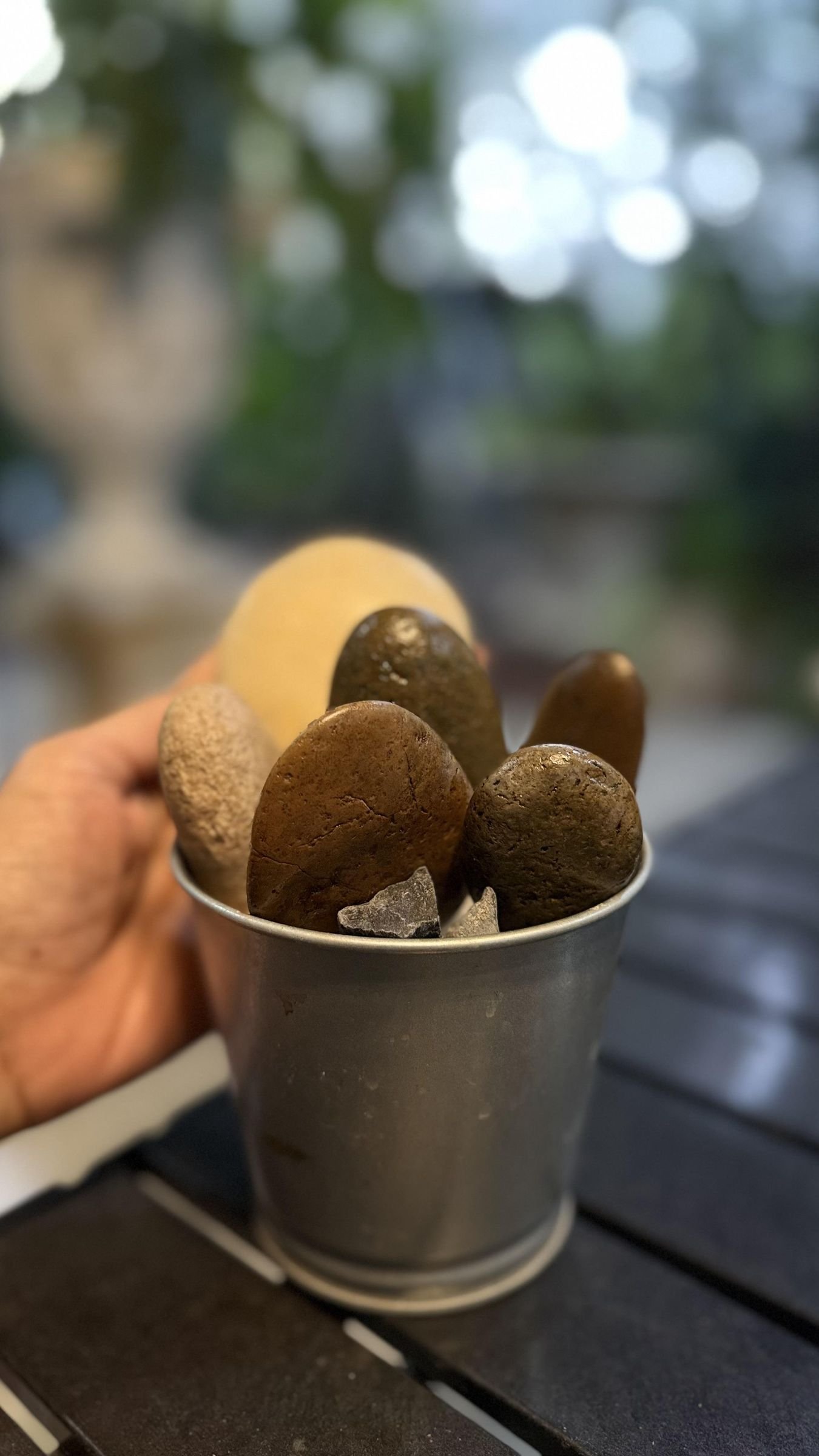 Unpainted stones test-arranged upright in a small metal planter