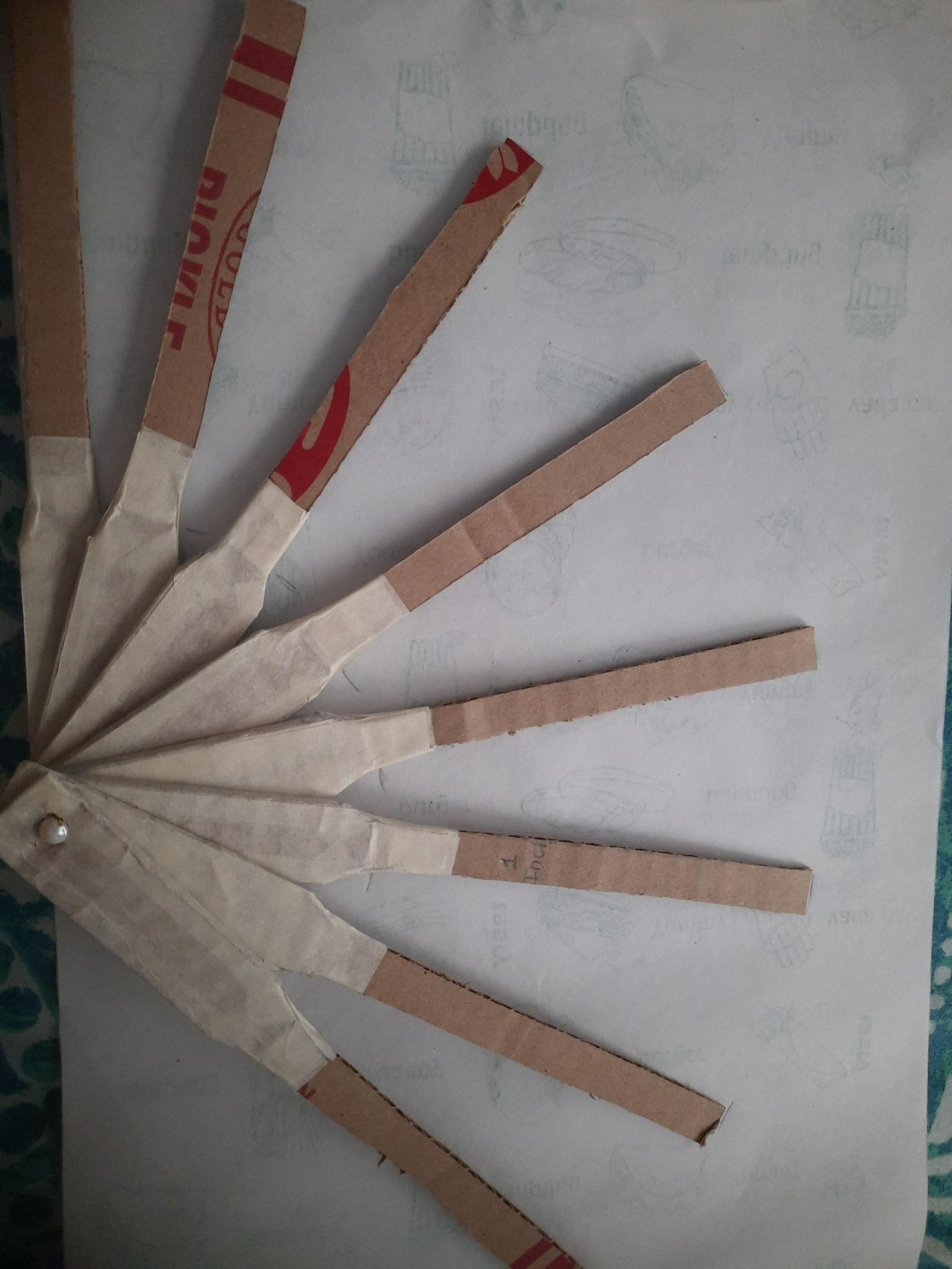 Assembled cardboard fan ribs spread into an arc around the wire pivot