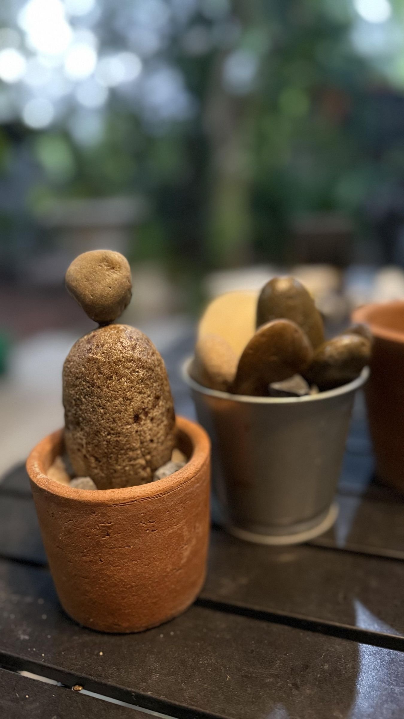 Unpainted stones test-arranged in terracotta and metal pots before painting