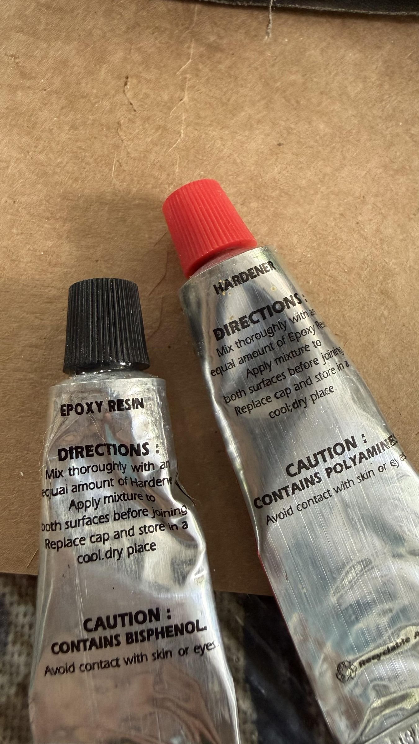 Two tubes of two-part epoxy resin and hardener with different colored caps