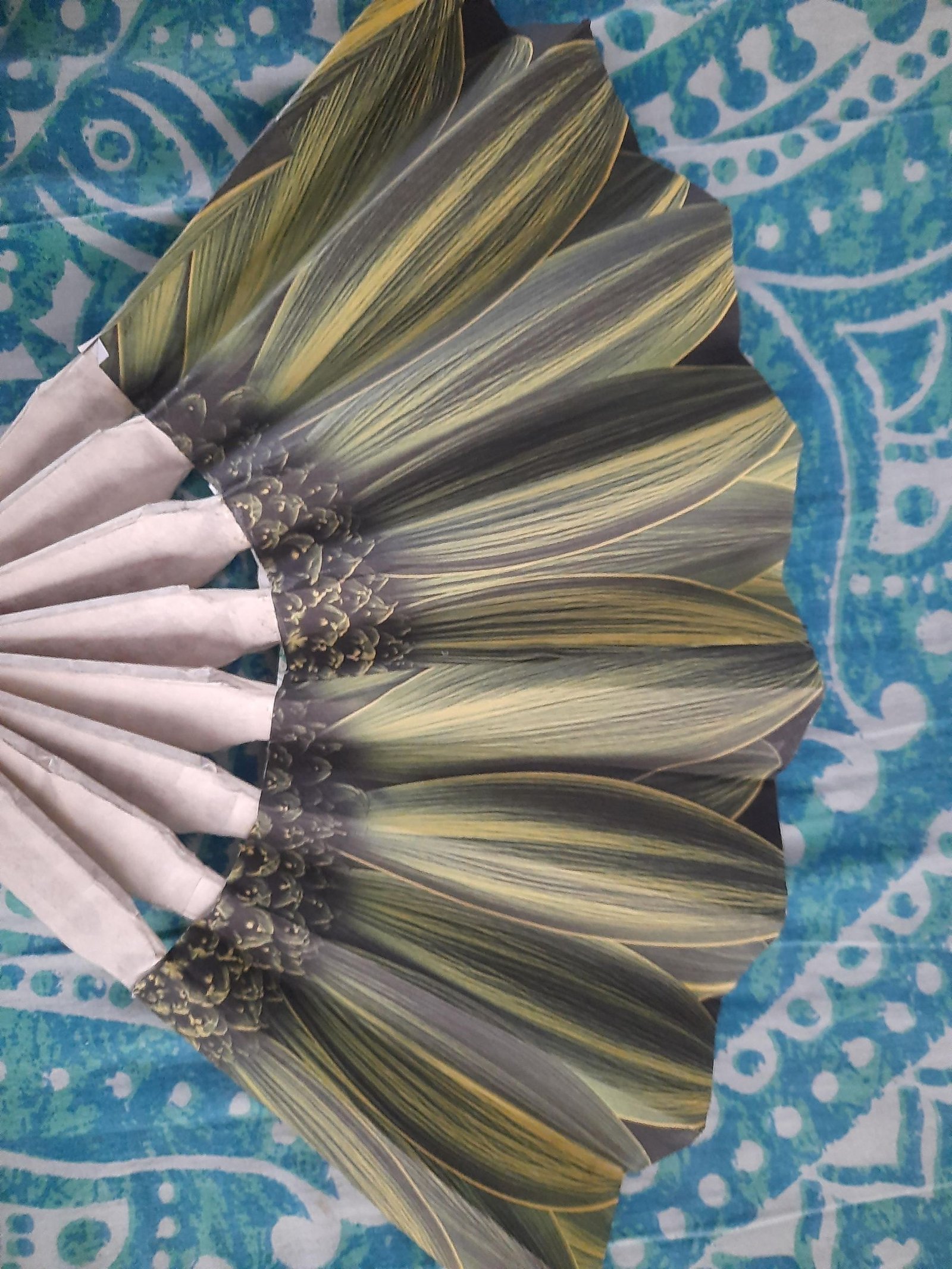 Completed folding fan with green botanical paper attached over the cardboard frame