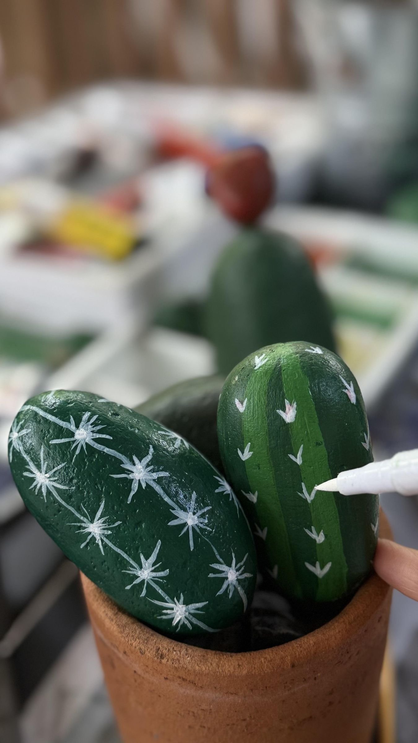 A white paint marker adding small arrow-shaped spines to an assembled cactus