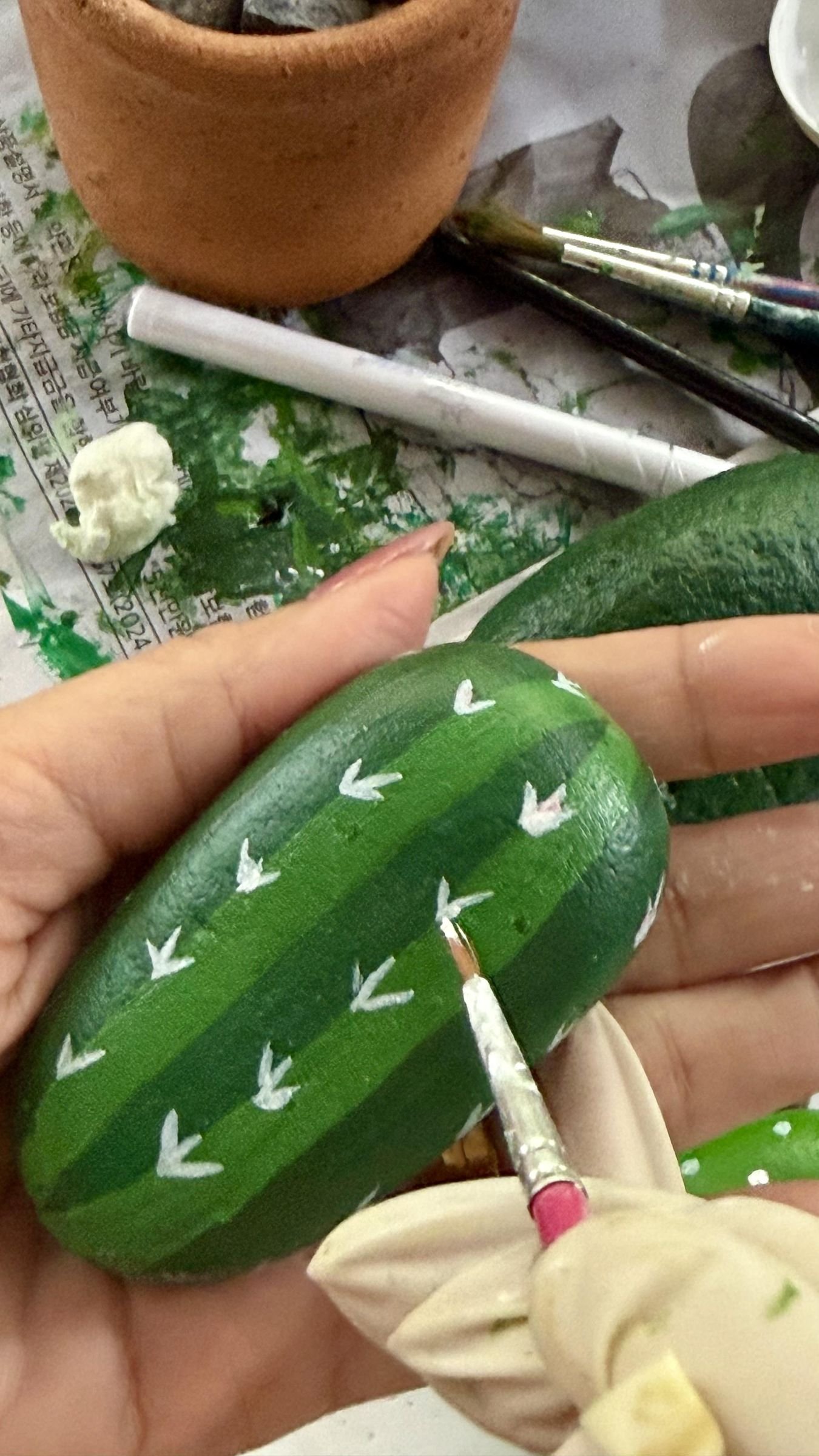 A fine brush painting rows of small white spine marks on a green stone