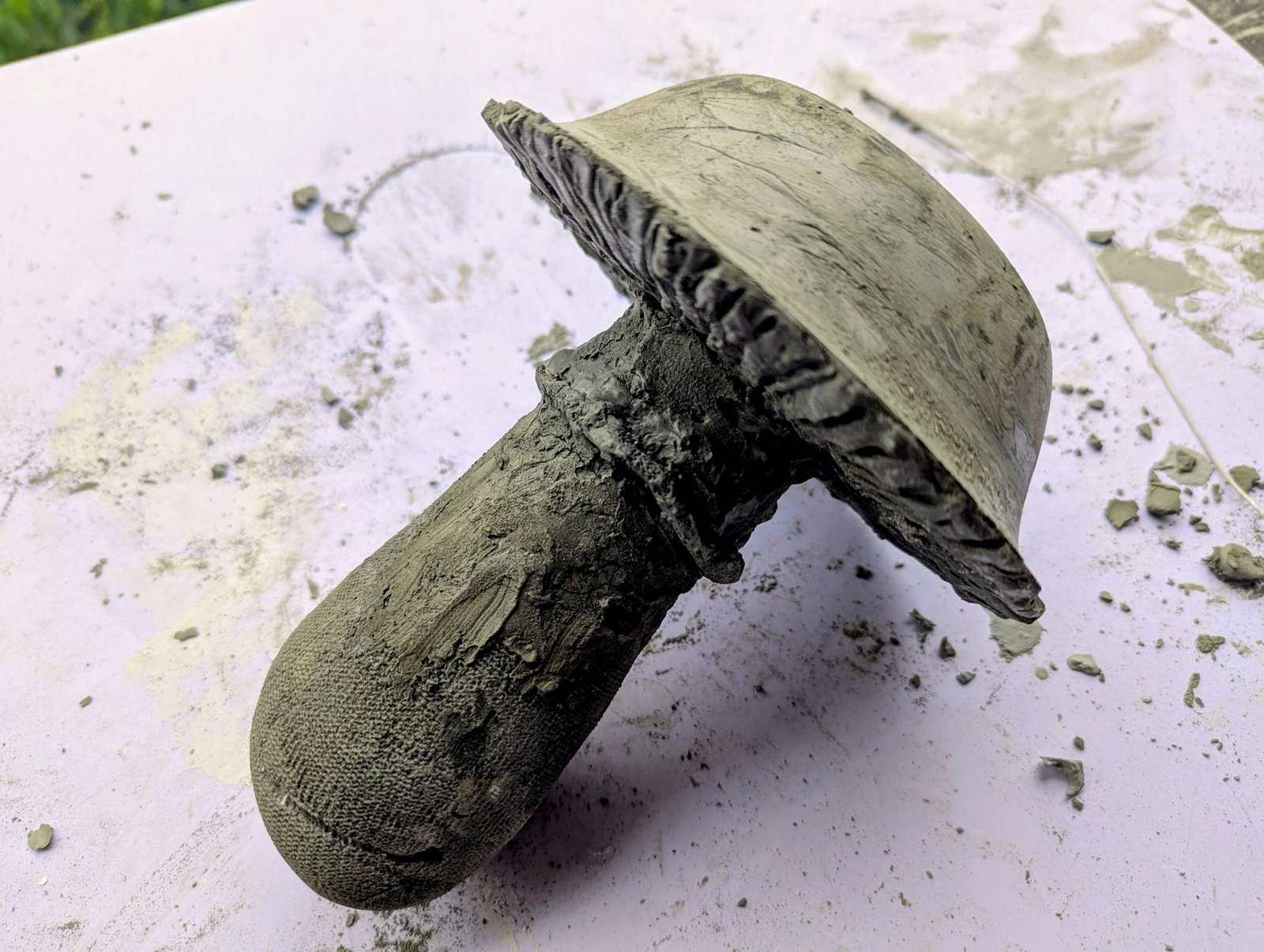 Unfinished large cement mushroom with a flat cap and rough stem