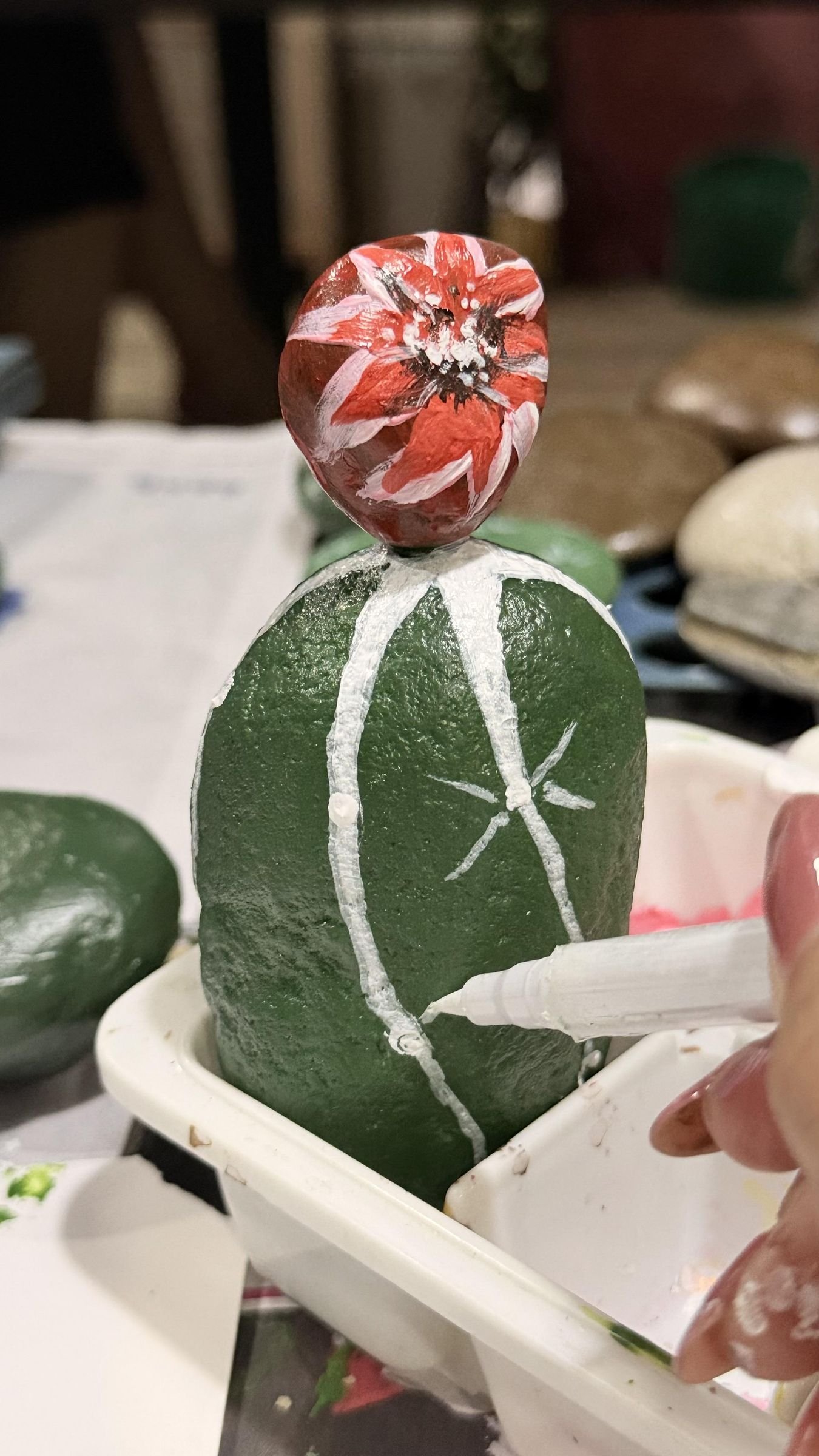 A small attached stone painted as a red-and-white cactus flower