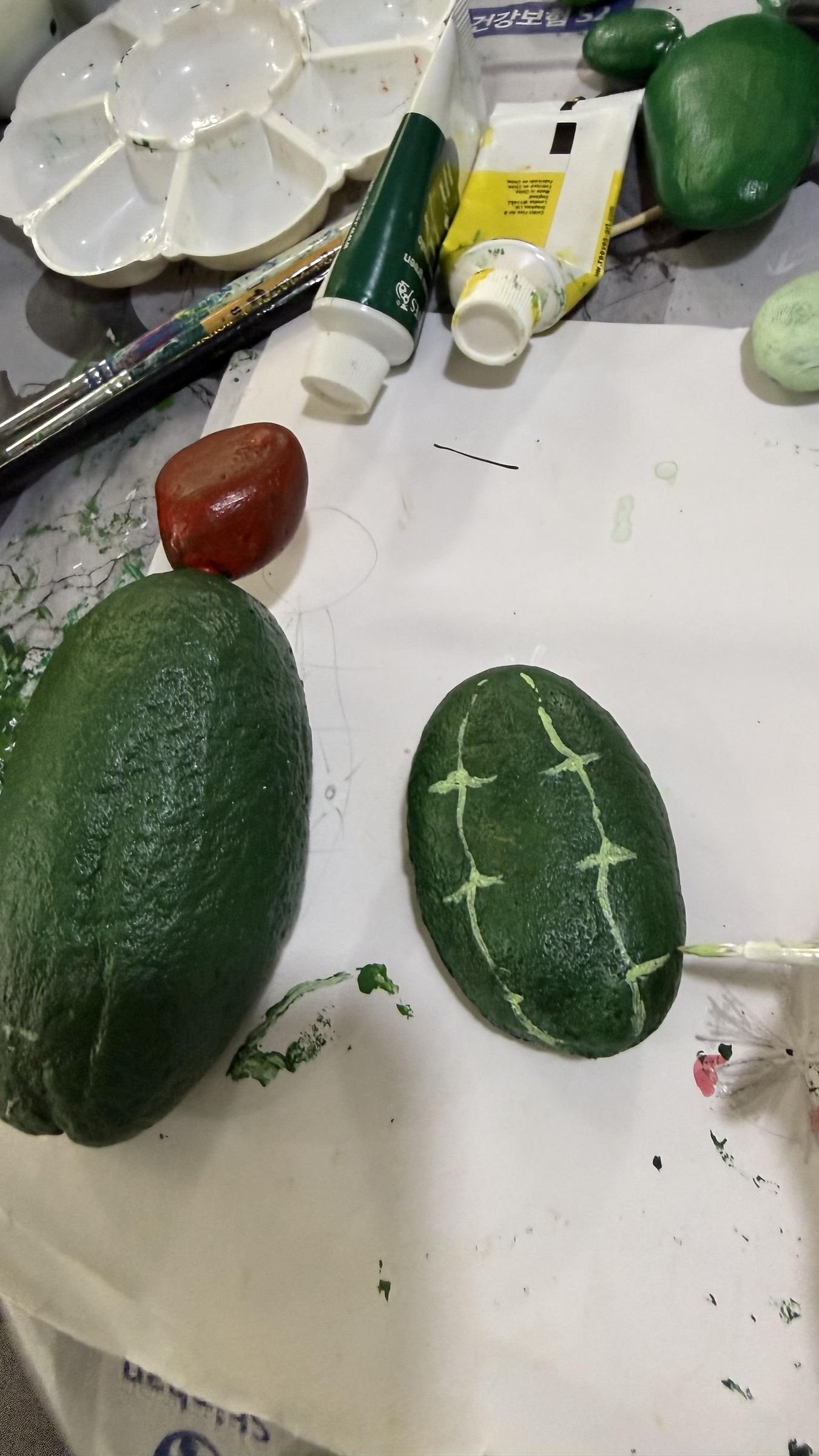 Green cactus stones with painted flower and spine details on the work surface