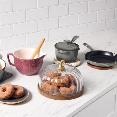 Pumpkin-shaped glass dome covering doughnuts on a kitchen counter