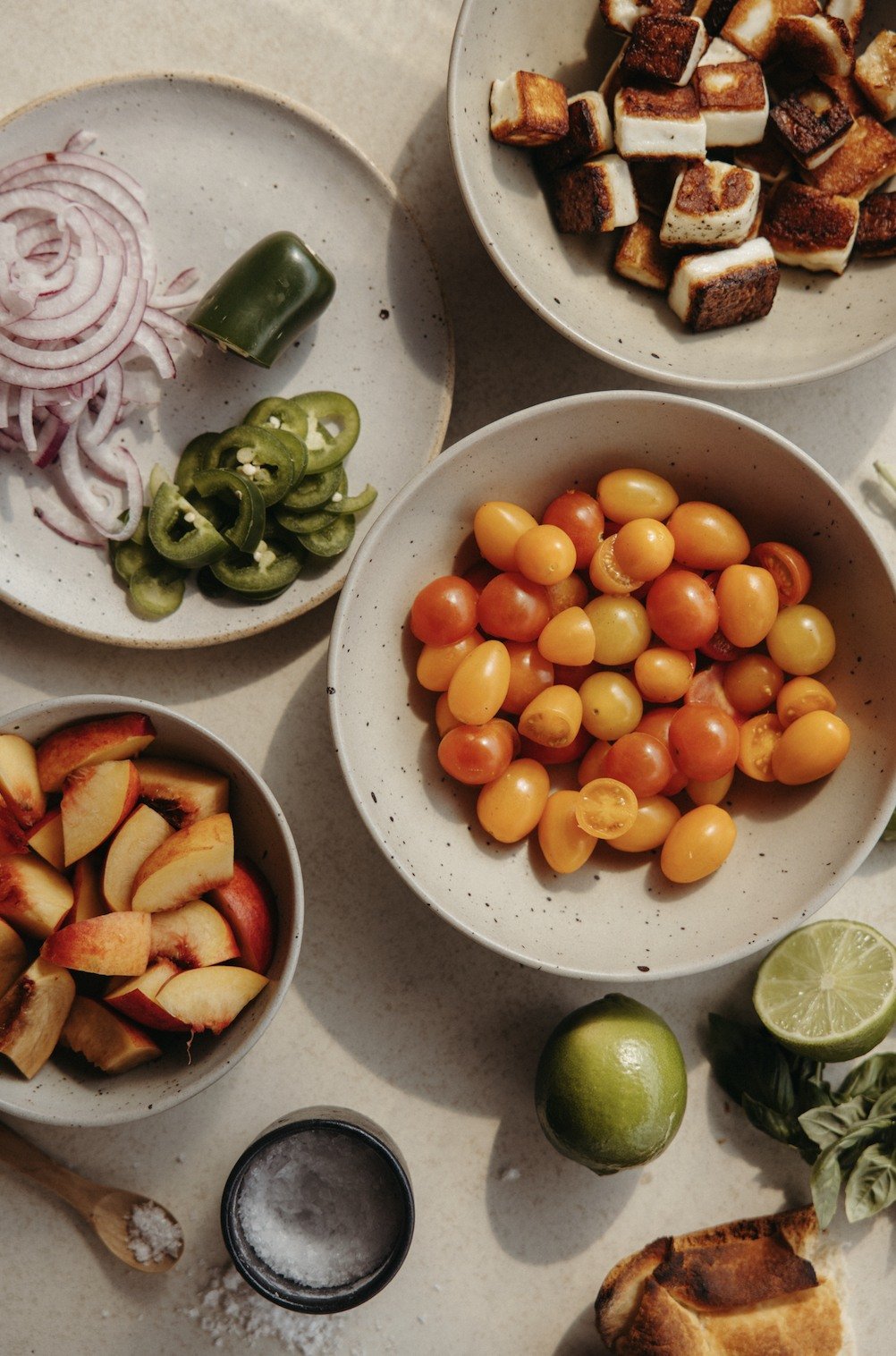 Cherry tomatoes, nectarines, red onion, jalapeño, lime, basil, and seared halloumi arranged in bowls