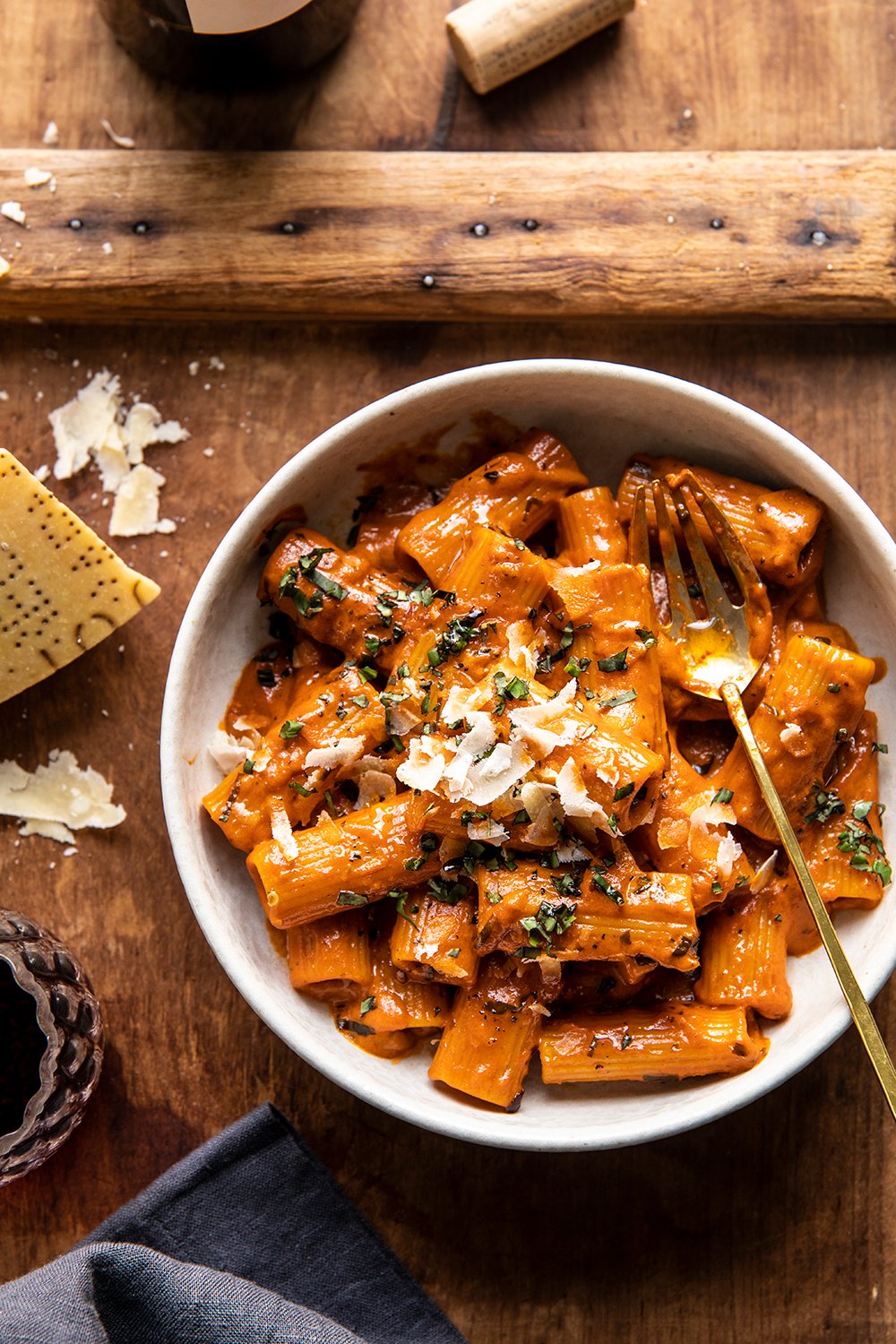 Bowl of rigatoni in creamy pesto vodka sauce topped with Parmesan and basil