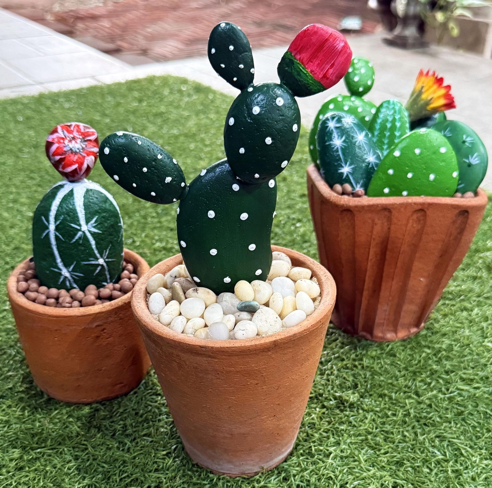 Three completed stone cactus planters grouped together on artificial grass