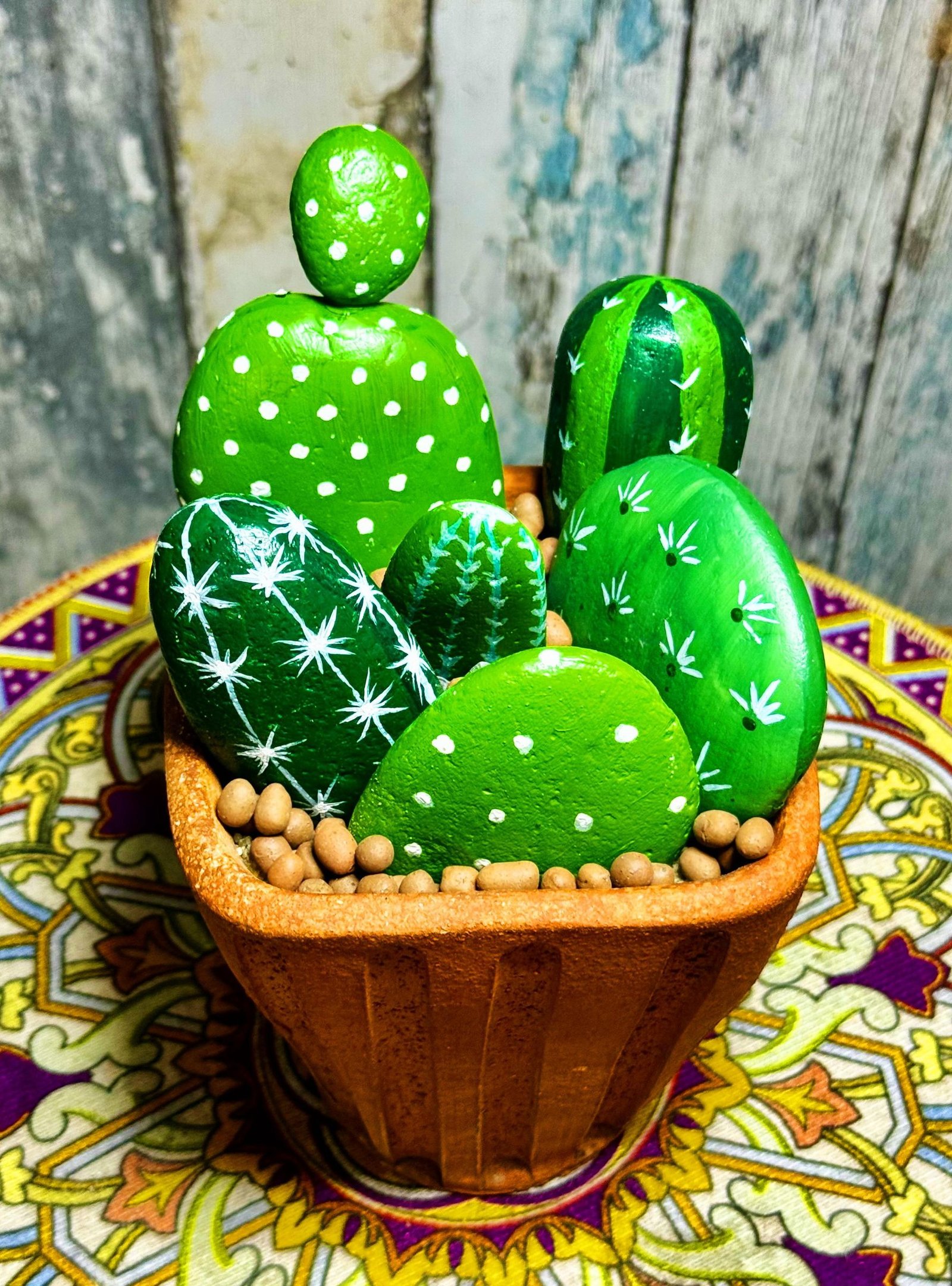 A completed mixed stone cactus planter displayed on a colorful patterned table