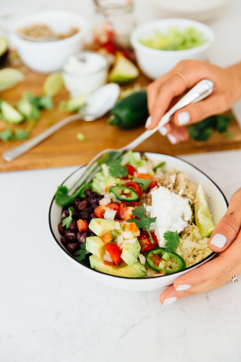 Chicken burrito bowl with rice, vegetables, avocado, and salsa