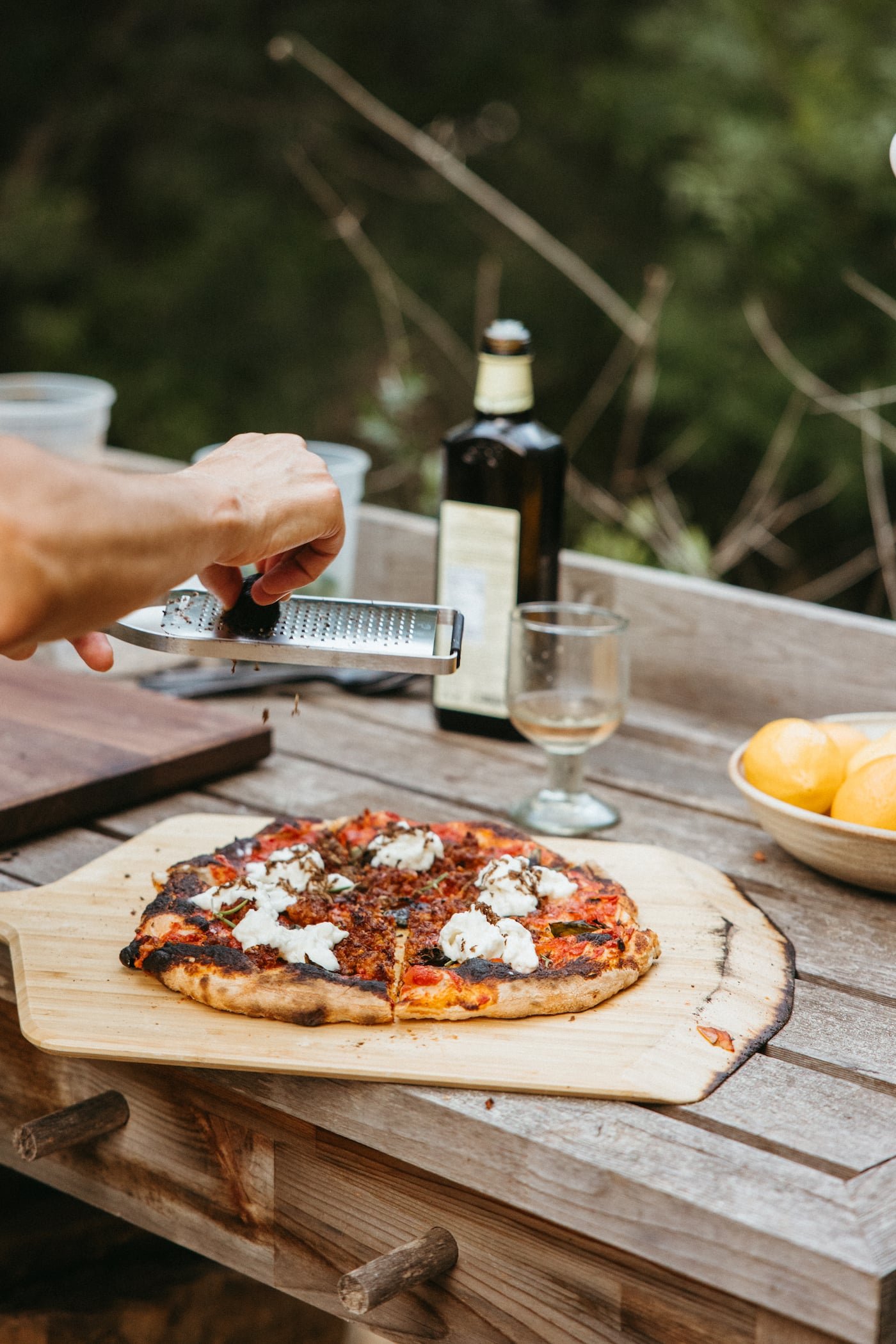 Parmesan being grated over a freshly baked pizza