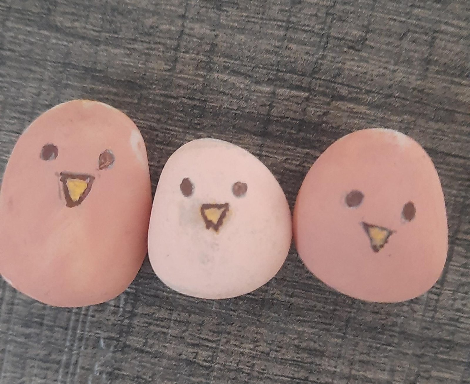 Three painted pebble sparrows with black eyes and yellow beaks