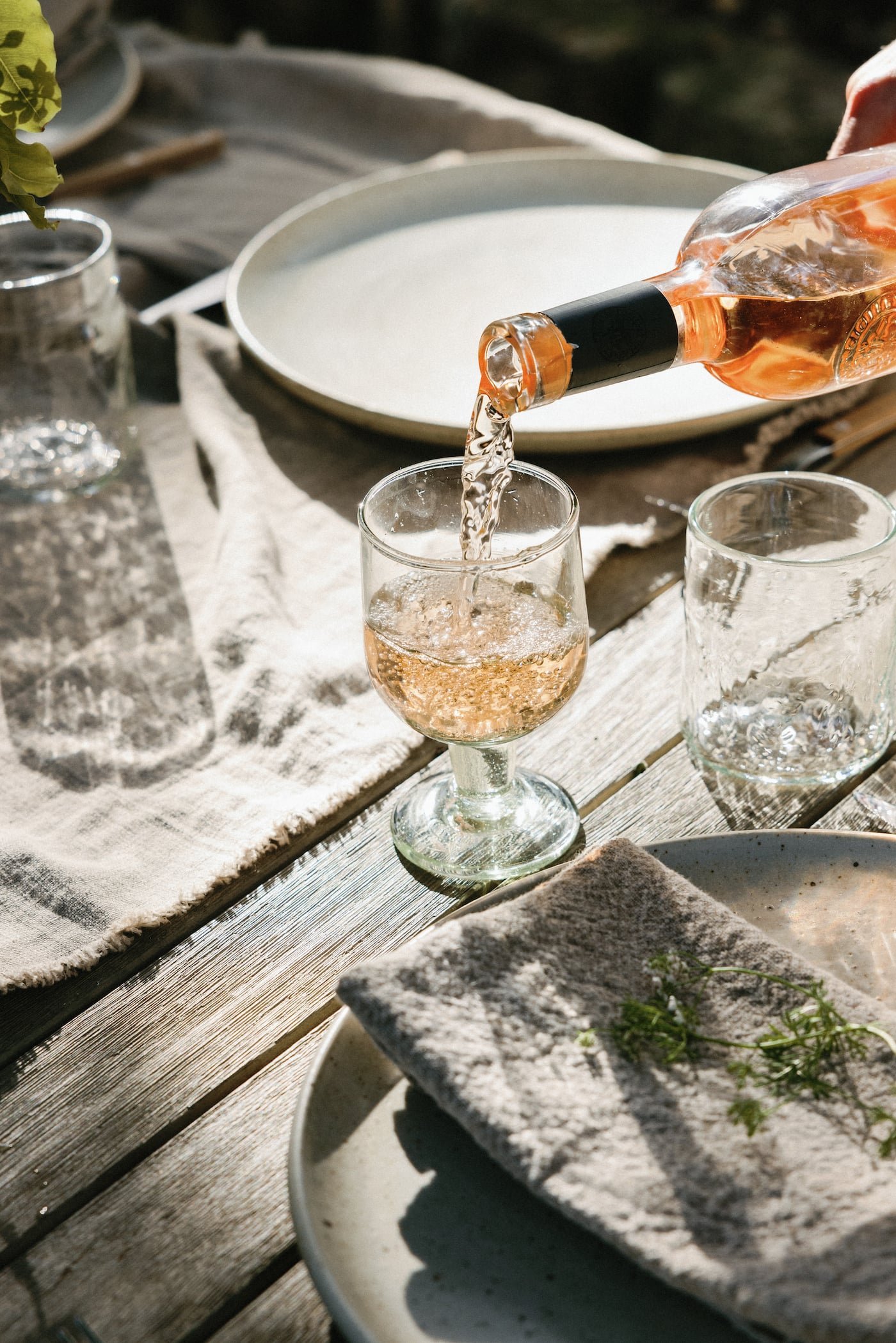 Rosé being poured into a coupe on a rustic outdoor table